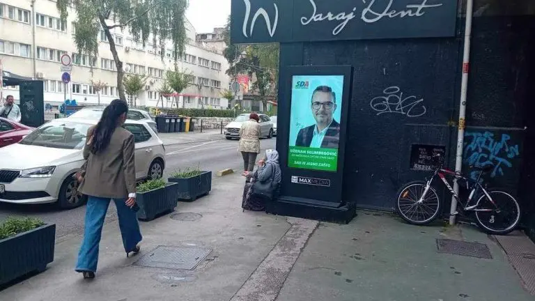Ovo je slika BiH: Starica prosi ispod plakata SDA, rezultat 30 godina vlasti